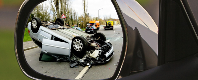 a car side mirror showing a car flipped on it's roof