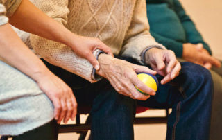 an old man sitting holding an exercise ball in one hand
