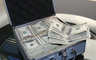 stacks of 100 dollar bills in a silver briefcase