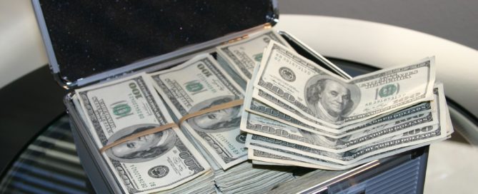 stacks of 100 dollar bills in a silver briefcase