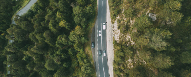 aerial view of cars on a roadway through a forest