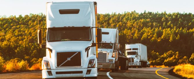 three tractor trailers in a row pulled to the side of a road