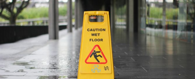 a wet sidewalk with a caution wet floor sign